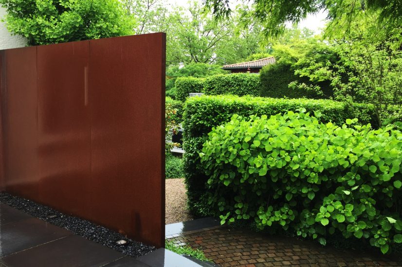 Natursteinmauer und Hecken als Sichtschutz in einem strukturierten Gartenraum